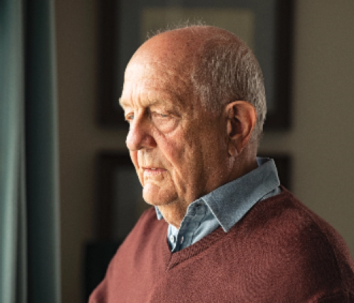 Older man in brown sweater looking sad