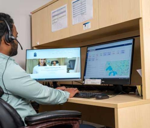 Man sitting at desk in front of two computer monitors