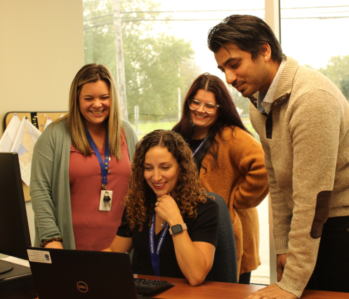 A group of people smiling and looking at a laptop screen