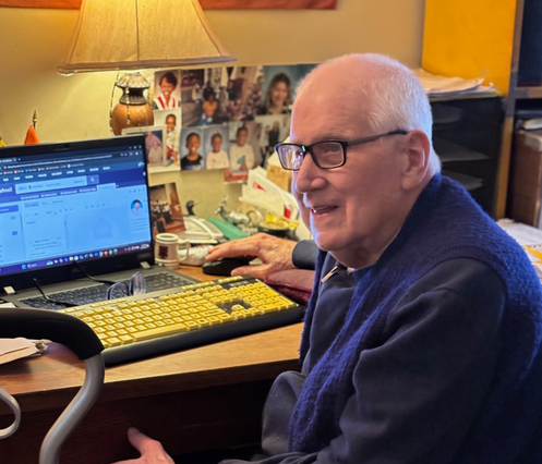 Photo of Hal in his home, sitting at a computer