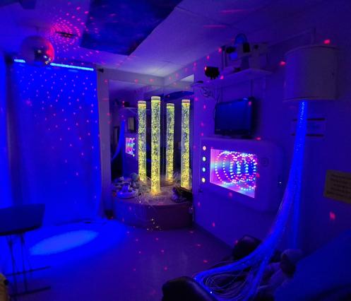 A blue lit room with sensory objects such as tall lava lamps and calming textures. 