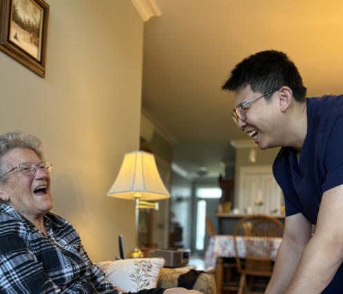 Continuing Care Assistant applying a compression stocking on a client on their sofa in their home.