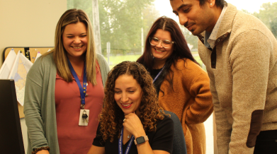 A group of people smiling and looking at a laptop screen