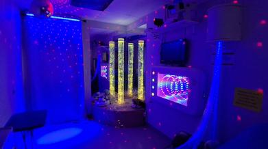 A blue lit room with sensory objects such as tall lava lamps and calming textures. 