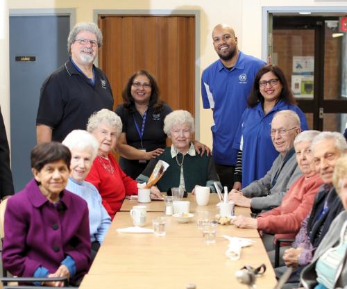 VON staff with clients sitting at a table together. They are all turned to smile at the camera. 